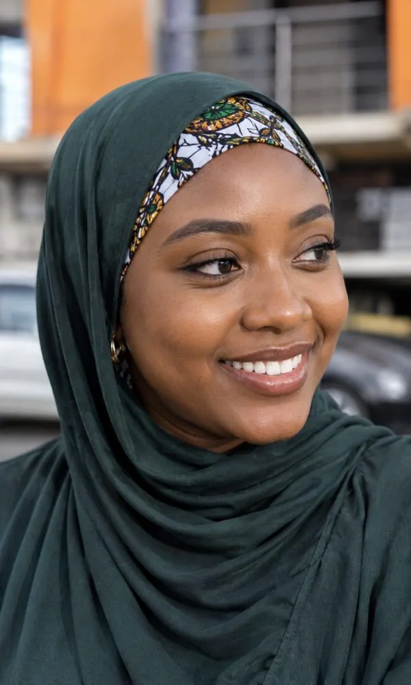 Woman wearing a bold patterned underscarf under a green hijab