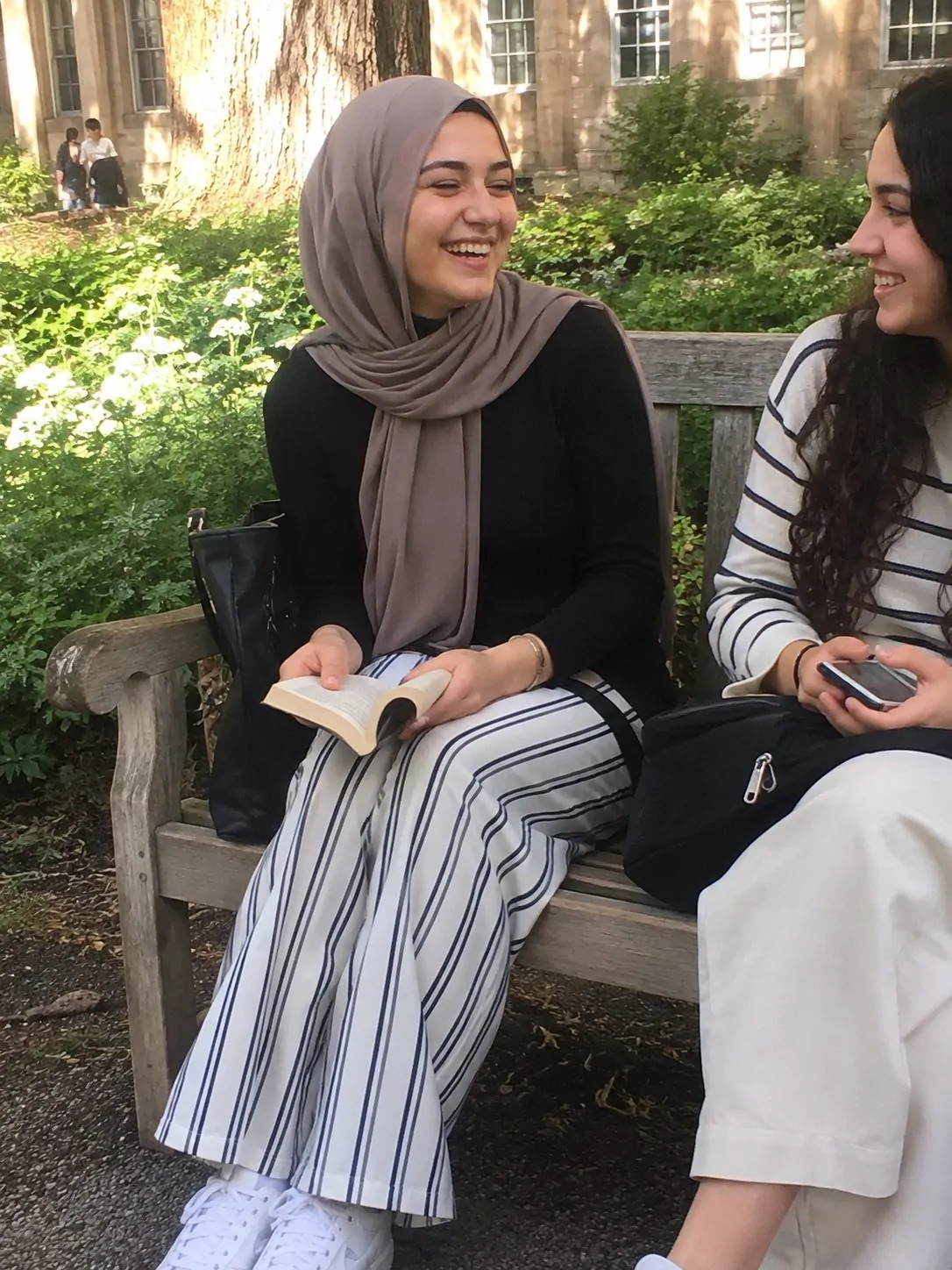 Hijabi girl in striped wide-leg trousers with a solid hijab on a study break