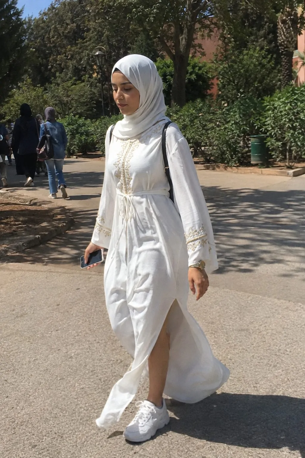 Hijabi girl in a flowing white embroidered maxi dress with side slit on campus